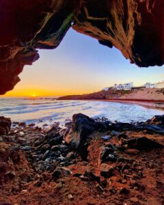 Fotografía de autor desde el interior de una cueva hacia la playa de El Porís de Abona, Tenerife, durante un atardecer con tonos cálidos y oleaje suave.