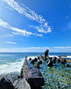 Fotografía Fine Art del litoral de Arona en Tenerife, mostrando piscina natural de agua cristalina entre rocas volcánicas bajo un cielo azul brillante con nubes dispersas.